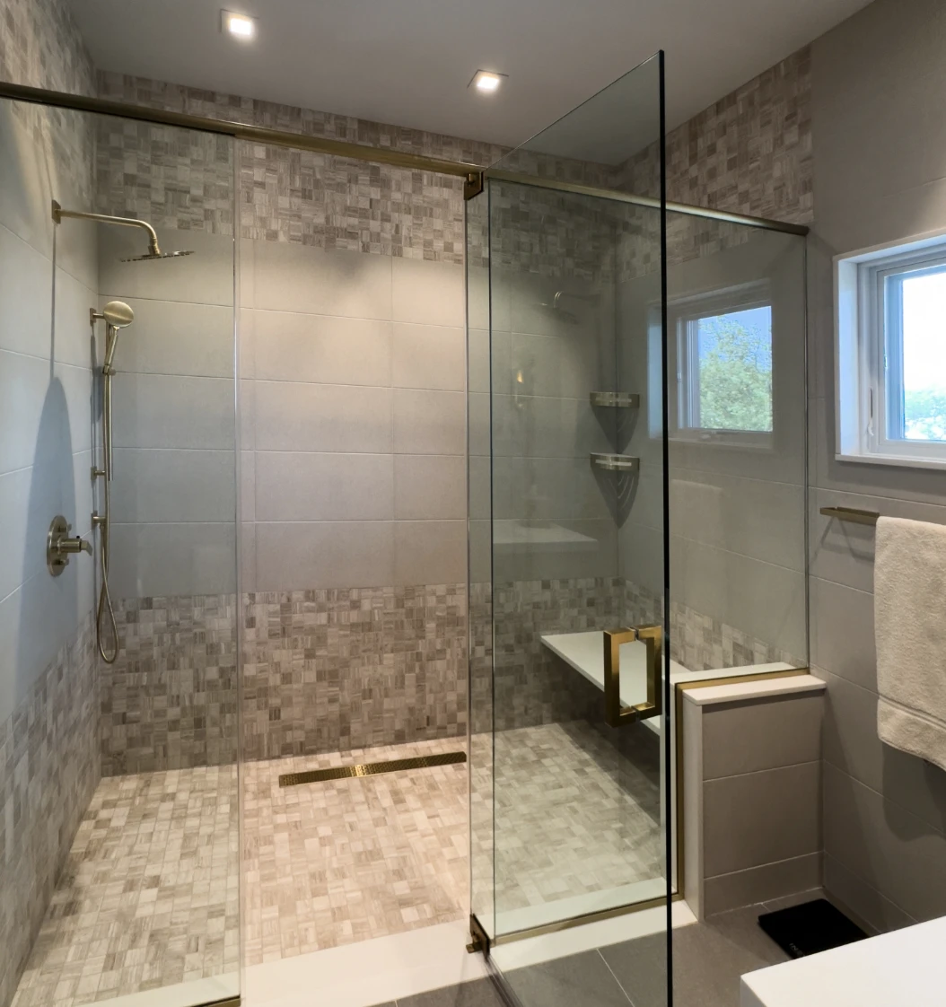 Sleek, frameless shower doors with pivot hinges and integrated seating, accented by satin gold accessories