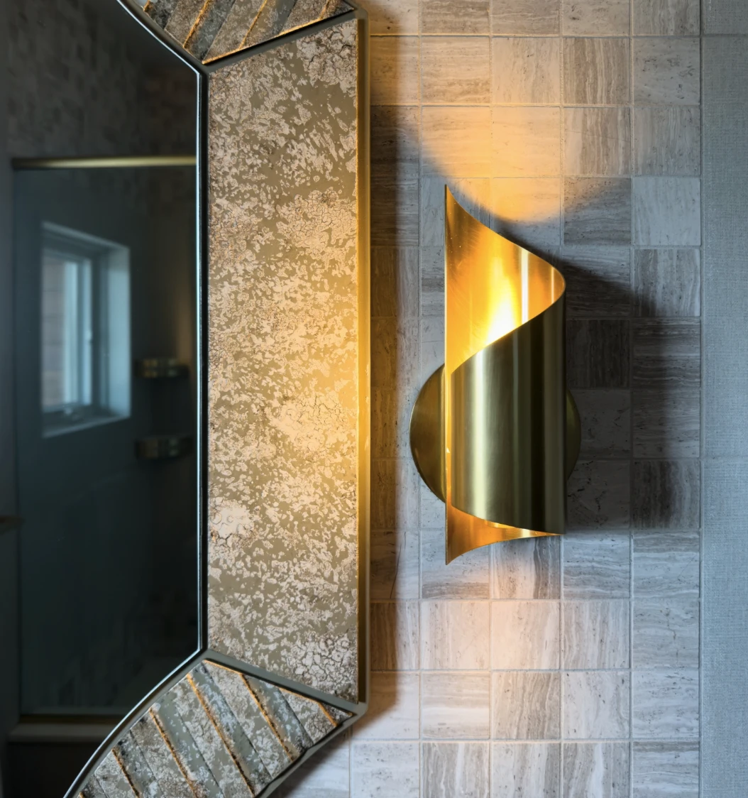 Feature sconce lighting frames the glamorous mirror, set off with mosaic tiles 