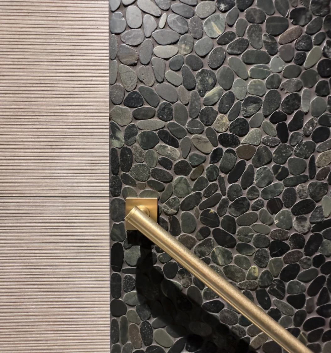 Functional and stylish diagonal grab bar on contrasting split stone and horizontal wall tiling 